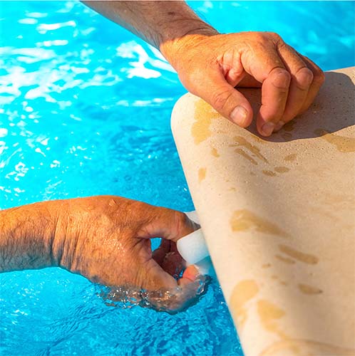 Pool service technician cleaning water edge scum line of a pool